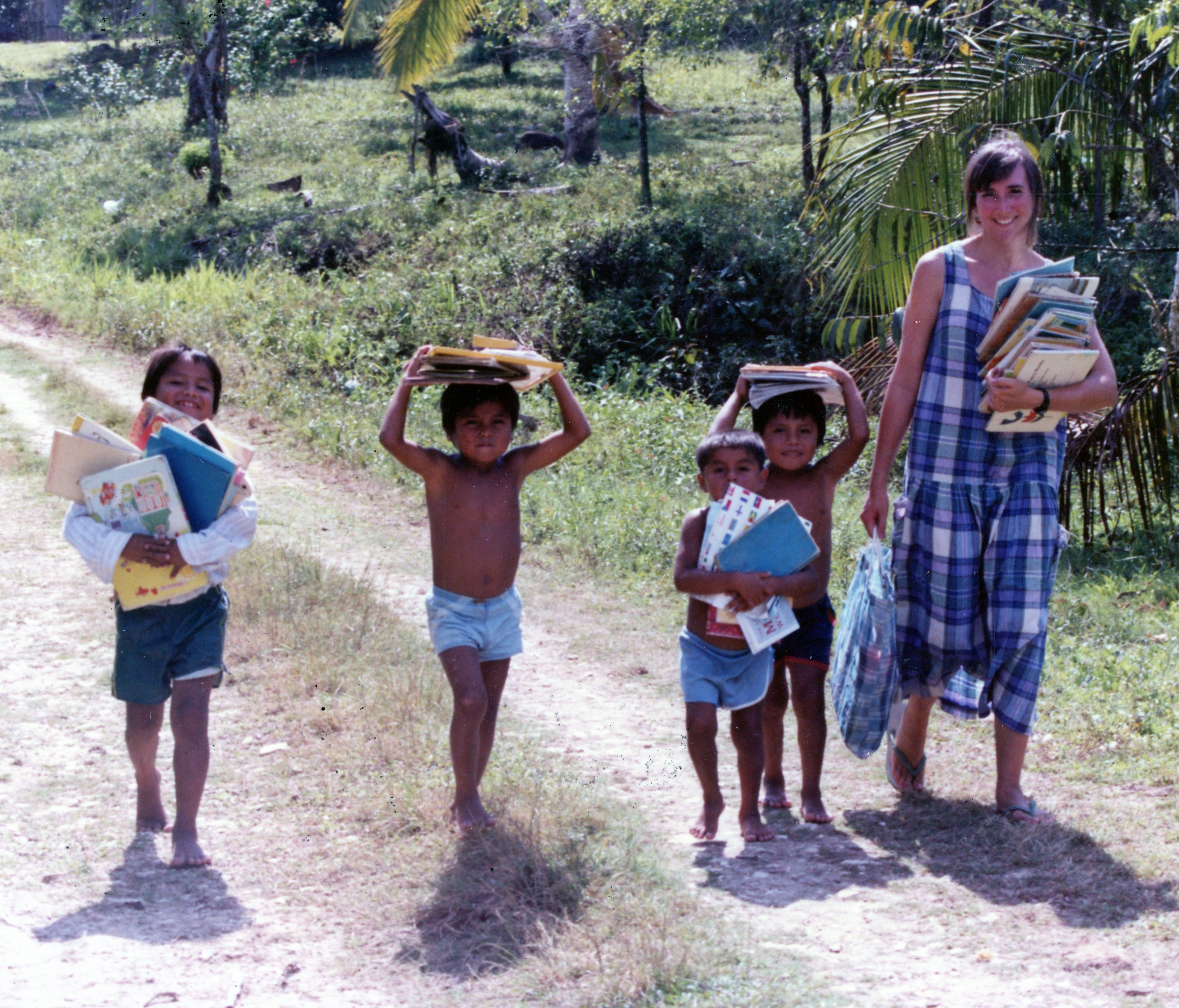 Teacher and small children carrying books